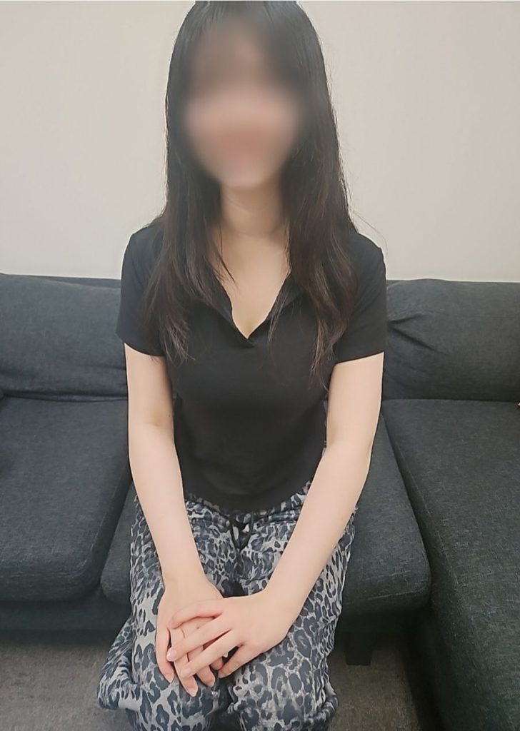 横浜関内の逆マッサージデリヘル、ハプニングランドの有村なのが服をきて座っている画像